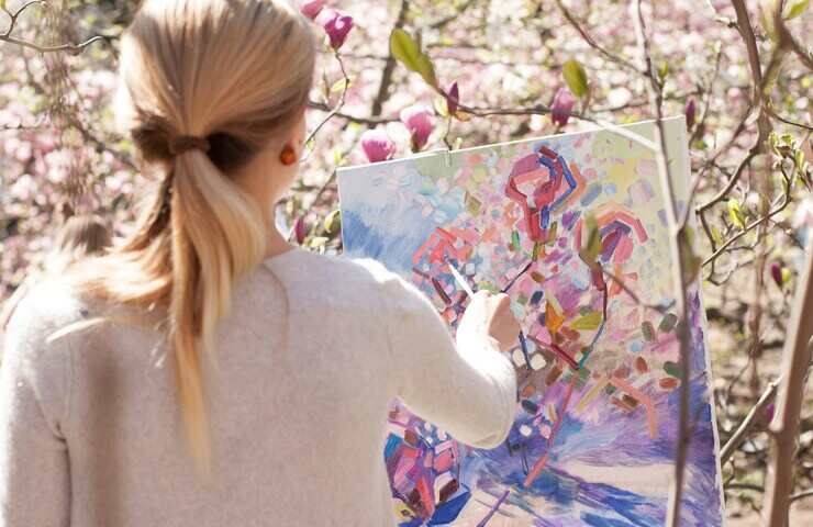 ragazza dipinge un albero fiorito sulla tela