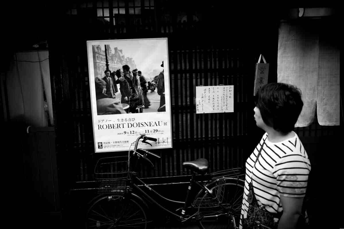 donna che guarda poster delle foto di Doisneau