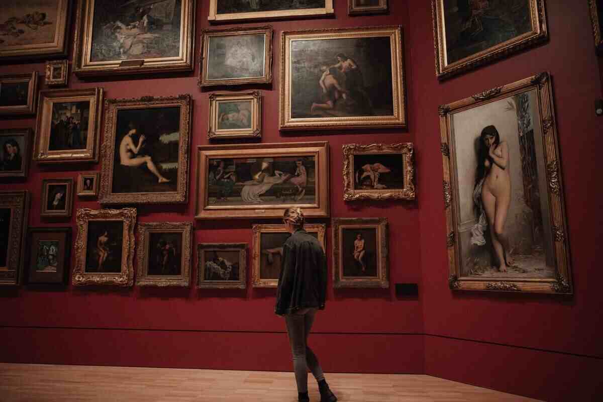 ragazza cammina per il corridoio di un museo osservando i quadri sulla parete